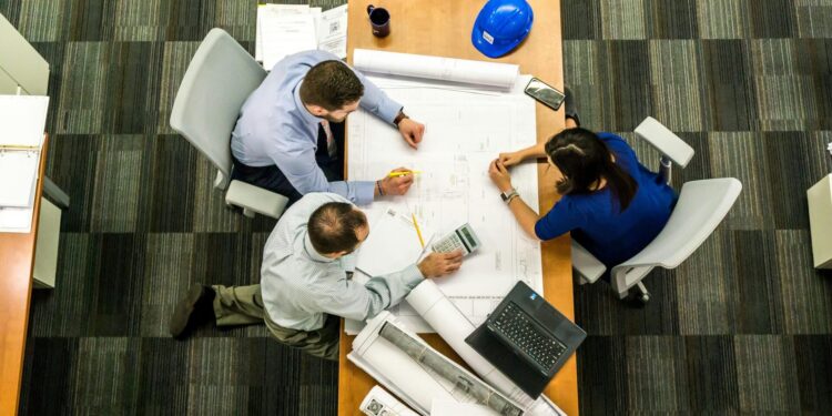 Top view of a team working on construction plans in an office setting.