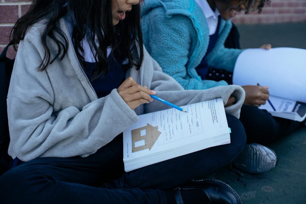 Two students studying with textbooks and collaborating outdoors, focusing on education.