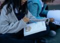 Two students studying with textbooks and collaborating outdoors, focusing on education.