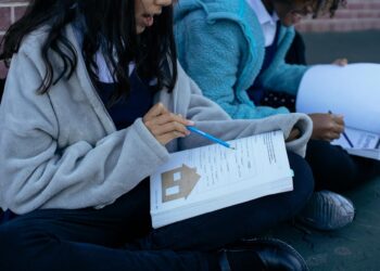 Two students studying with textbooks and collaborating outdoors, focusing on education.