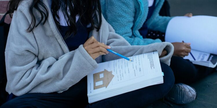 Two students studying with textbooks and collaborating outdoors, focusing on education.