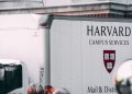 Harvard Campus Services truck in city street, showcasing delivery near university building.