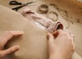 Close-up of hands wrapping a linen shirt with twine, showcasing craftsmanship and sustainable fashion.