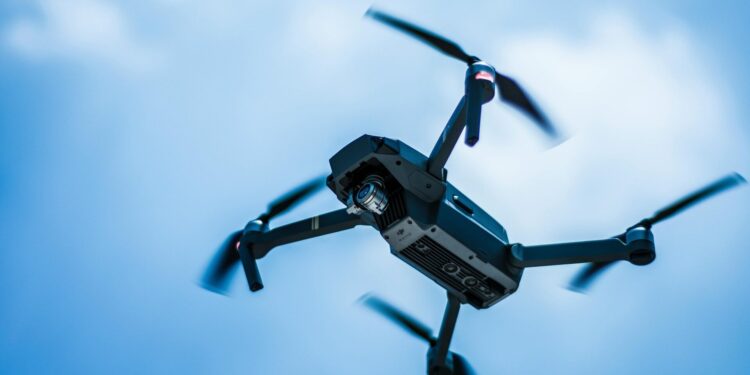 A sleek drone captures the sky in action with a clear blue background, showcasing modern technology.