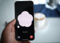 Close-up of a smartphone in hand with AI voice chat bubble and coffee in background.