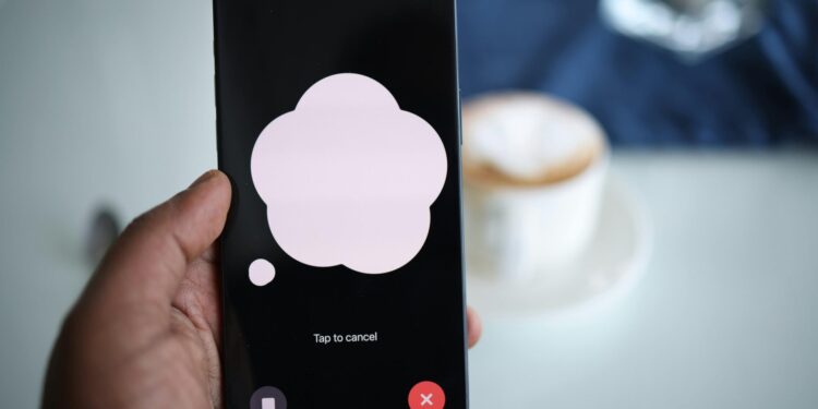 Close-up of a smartphone in hand with AI voice chat bubble and coffee in background.