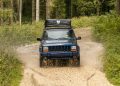 A rugged 4x4 vehicle navigates through muddy trails in the Asiago forests of Italy, showcasing adventure and nature.