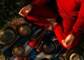 A person meditating outdoors with Tibetan singing bowls, creating a peaceful atmosphere.