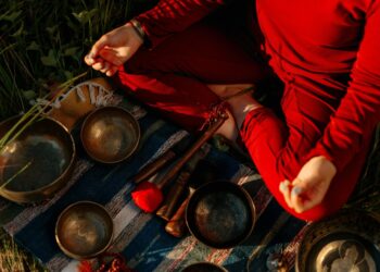 A person meditating outdoors with Tibetan singing bowls, creating a peaceful atmosphere.