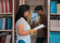 Two students studying among bookshelves in a New Delhi library.