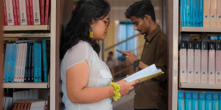 Two students studying among bookshelves in a New Delhi library.