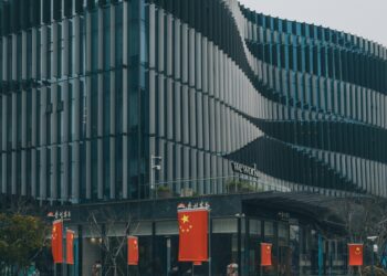 Contemporary architectural building with Chinese flags displayed prominently.