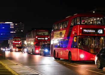 Red double-decker buses in London's nighttime traffic, showcasing urban life.