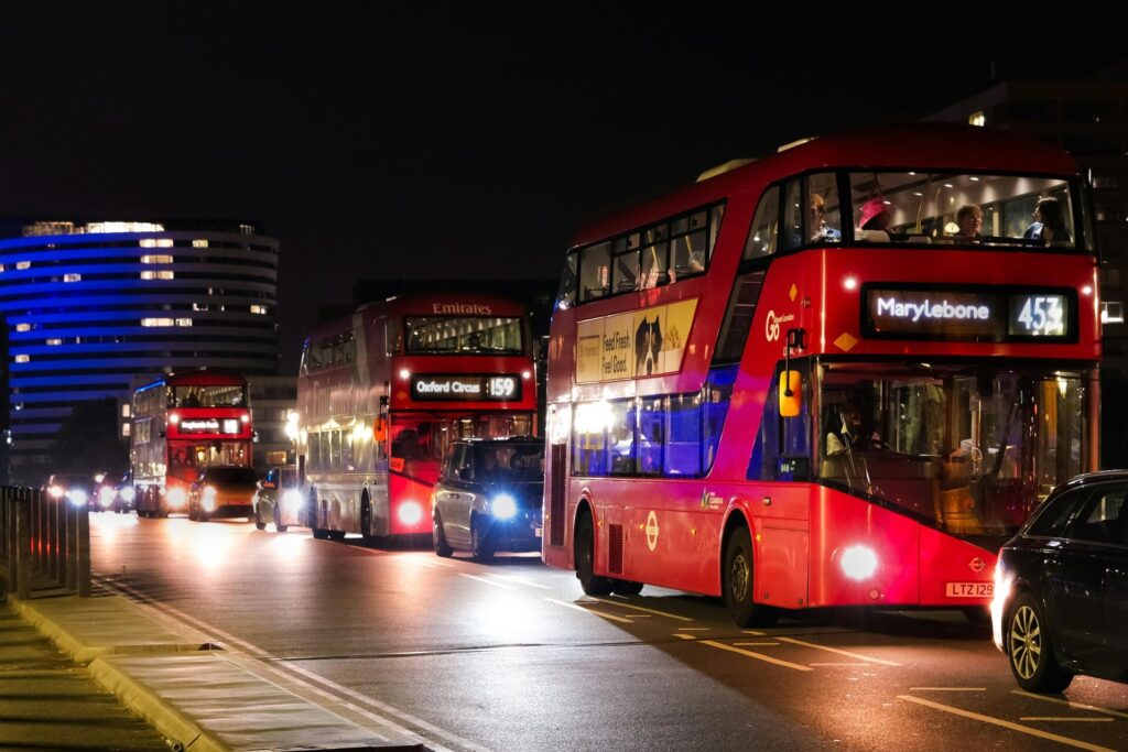 Red double-decker buses in London's nighttime traffic, showcasing urban life.