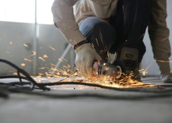 A skilled industrial worker uses a grinder creating a burst of sparks indoors.