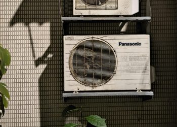 Close-up of two air conditioning units on a building facade in sunlight.