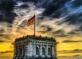 Vibrant sunset over a historic Berlin monument with the German flag waving.