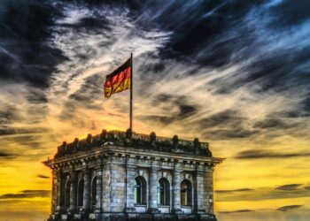 Vibrant sunset over a historic Berlin monument with the German flag waving.