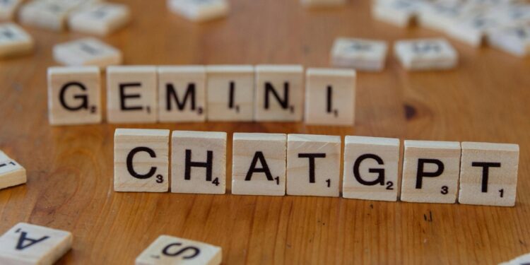 Close-up of wooden Scrabble tiles spelling Gemini and ChatGPT on a wooden surface.