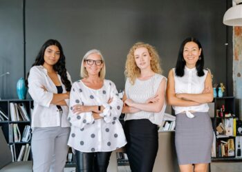 Four professional women standing confidently in an office, symbolizing diversity and teamwork.