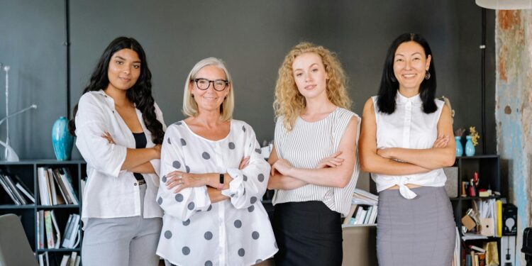 Four professional women standing confidently in an office, symbolizing diversity and teamwork.
