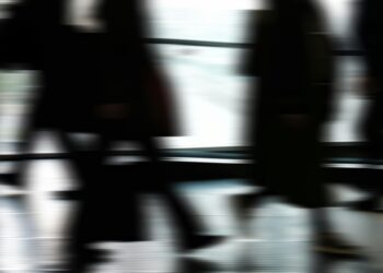 Abstract blurred motion of people walking indoors, depicting urban life and busy routines.