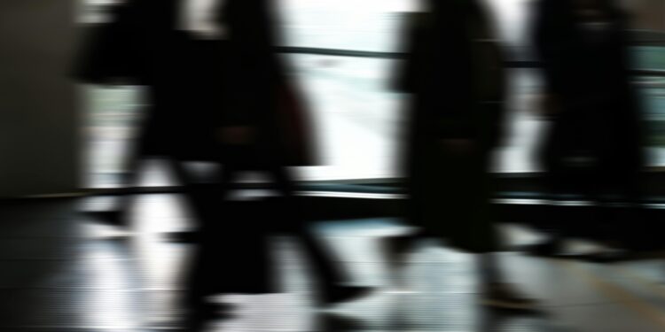 Abstract blurred motion of people walking indoors, depicting urban life and busy routines.