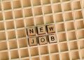 Discover the excitement of a new job with wooden letter tiles spelling 'NEW JOB' on a grid.