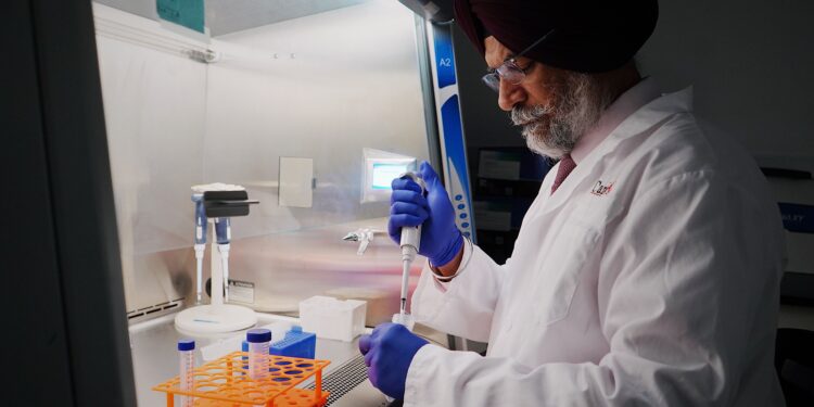 Scientist in lab coat using pipette in sterile lab. Focused research work in laboratory setting.