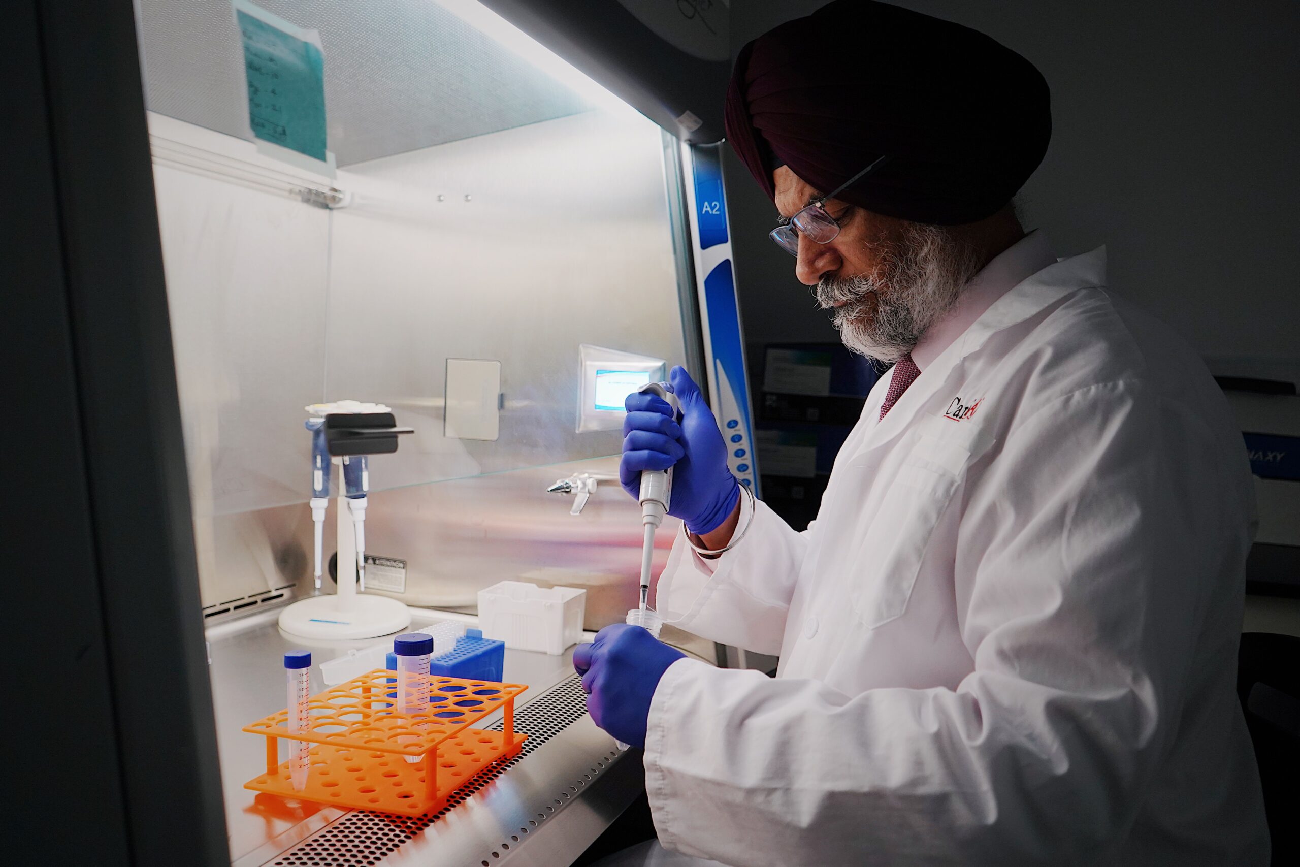 Scientist in lab coat using pipette in sterile lab. Focused research work in laboratory setting.