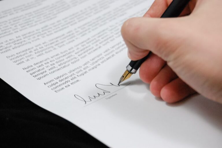 A hand signing a legal document with a fountain pen, illustrating the agreement between Axis Bank and IIM Bangalore.