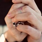 Two hands with tattoos clasped together, one wearing a ring, illustrating union solidarity in the article.