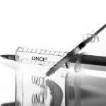 A syringe and vaccine vial on a medical surface, illustrating the pharmaceutical context of Eli Lilly's obesity drug outlook.