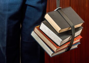 A student studying beside a pile of books, illustrating the need for AI assessment before university AI curricula.
