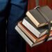 A student studying beside a pile of books, illustrating the need for AI assessment before university AI curricula.