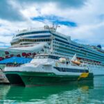 A cruise ship and ferry docked in Antigua's turquoise waters, illustrating the cruise industry's fuel strategies.