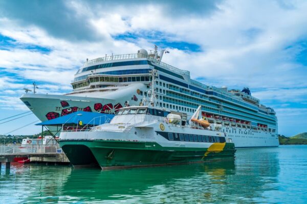 A cruise ship and ferry docked in Antigua's turquoise waters, illustrating the cruise industry's fuel strategies.