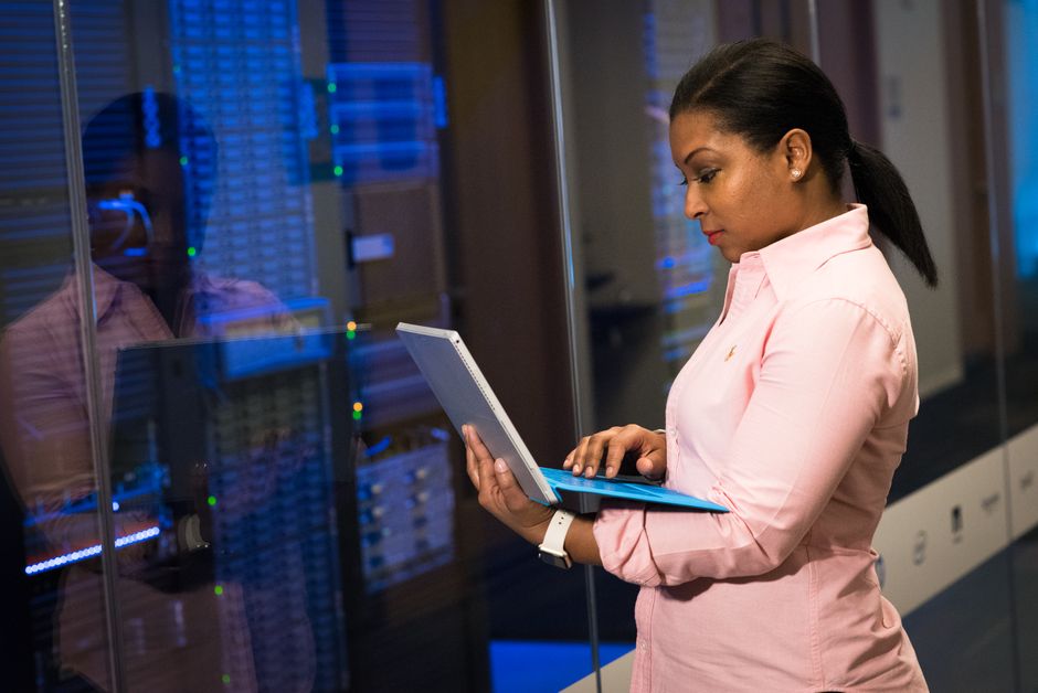A focused software engineer works on a laptop in a server room, illustrating the tech career he considers leaving for farming.