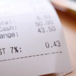 A close-up of a shopping receipt showing GST and total charges, illustrating the foundation's support payment of £158 to the poorest half.