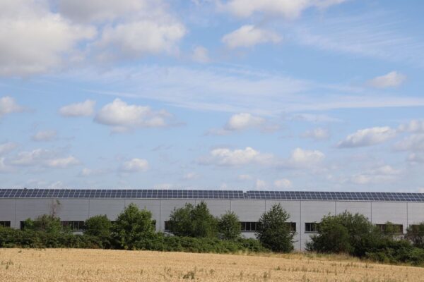 A countryside warehouse with solar panels and fields under a blue sky, illustrating India's data centre investment potential.