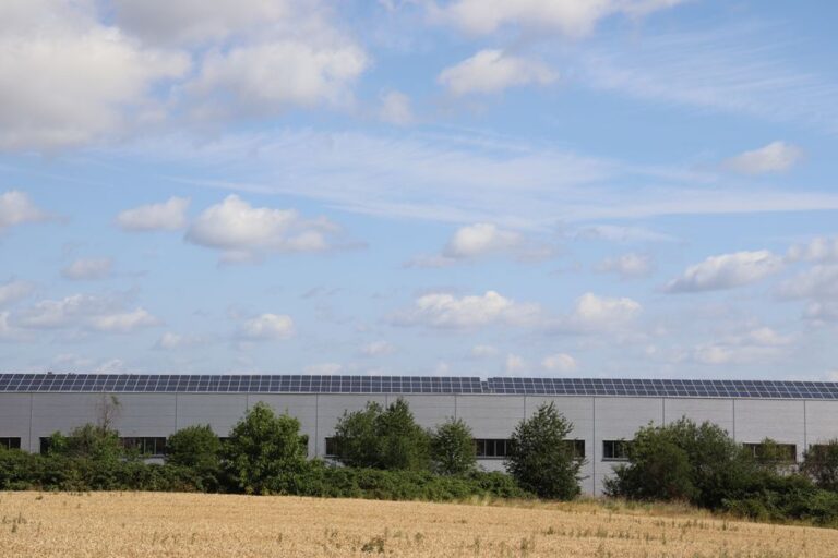 A countryside warehouse with solar panels and fields under a blue sky, illustrating India's data centre investment potential.