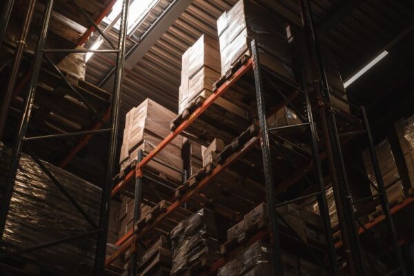 Stock photo of interior view of a warehouse with stacked cardboard boxes on high shelves, showcasing storage, used to illustrate this story on Poundland Owner Faces Administration as Reynolds Seeks Facts.