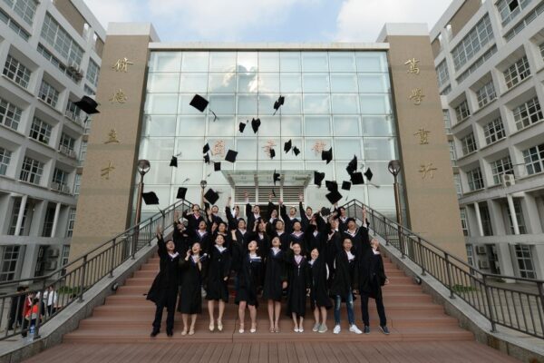 Students tossing graduation caps outside a school building, illustrating former students' legal disputes over loan discharges.