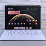 A sleek tablet with a keyboard showing a digital interface on a wooden background, illustrating the touchscreen MacBook Pro launch.