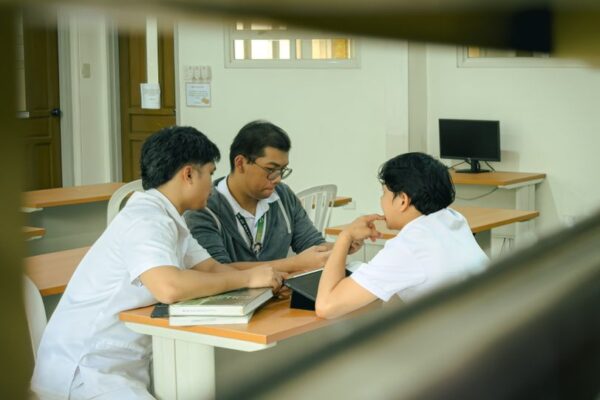 Three students collaborating on a classroom project, illustrating college teamwork amid digital wagering concerns.