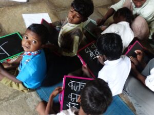 Young students writing on slates in a village school, illustrating calls to prepare students for creator-economy jobs.