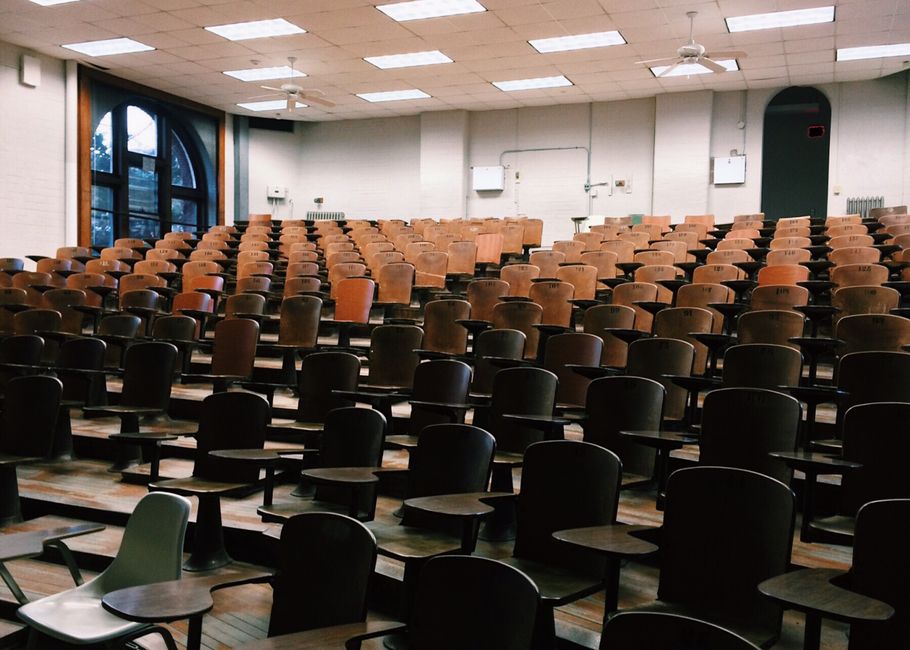 Stock photo of empty university lecture hall with wooden chairs and large windows, used to illustrate this story on Australia’s Study Appeal Falls as UK and US Gain.