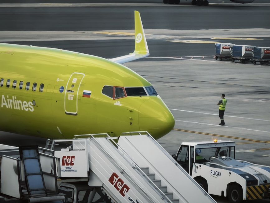 Stock photo of A vibrant green passenger aircraft parked on an airport runway with luggage and ground, used to illustrate this story on MIAL Sets November 3 Deadline for Navi Mumbai Flight Plans.