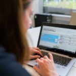 Stock photo of A woman engineer focuses on software analysis using a laptop indoors, used to illustrate this story on Software Engineer Considers Farming as AI Advances.