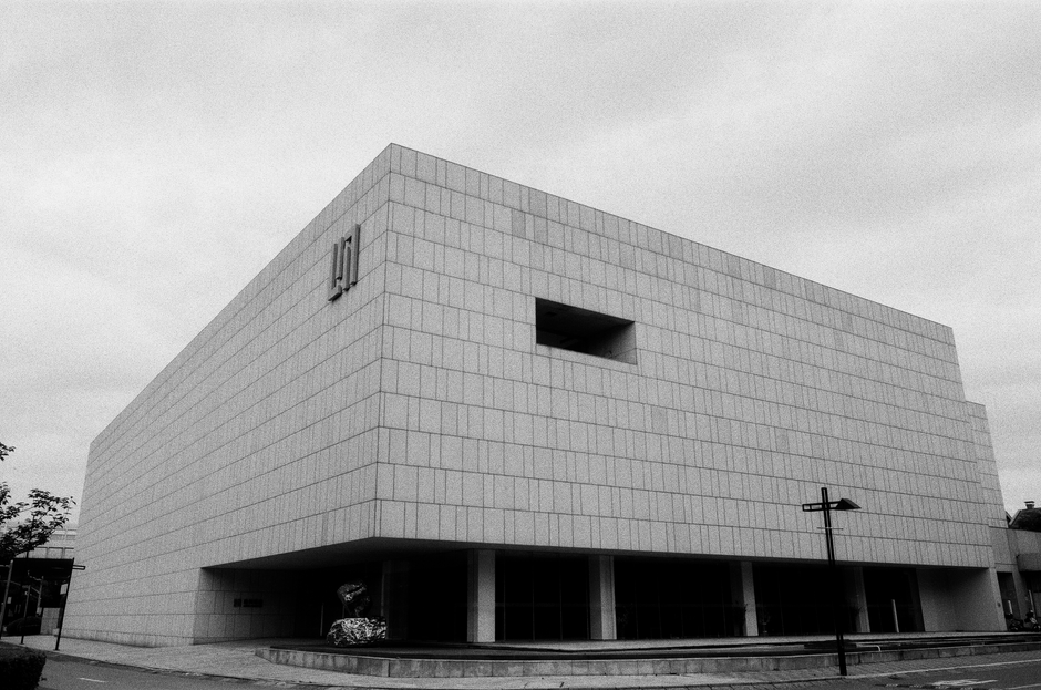 A modern minimalist museum building exterior in black and white, illustrating the Crystal Bridges expansion in Bentonville.